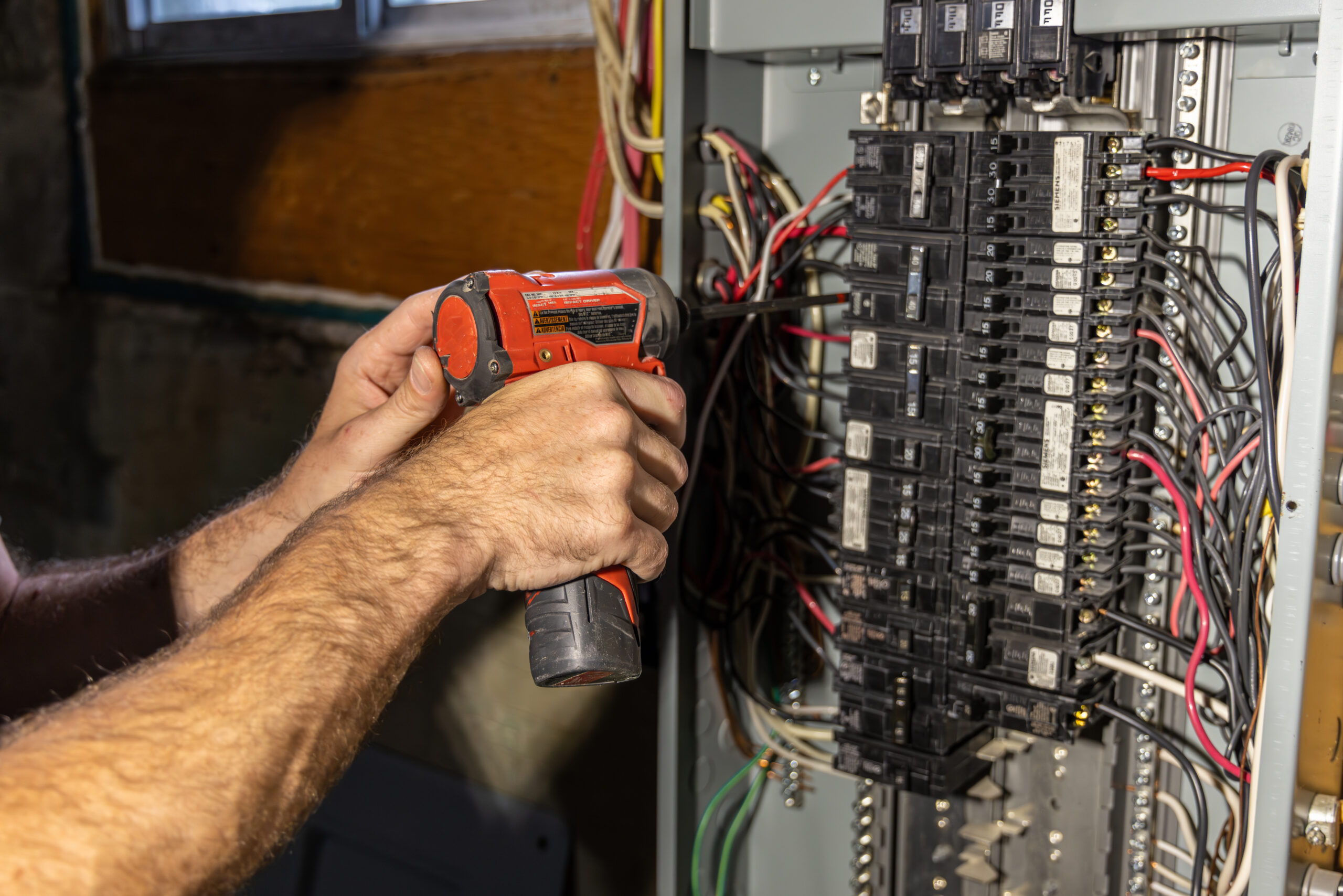 Electrician installing a ground wire in a breaker box